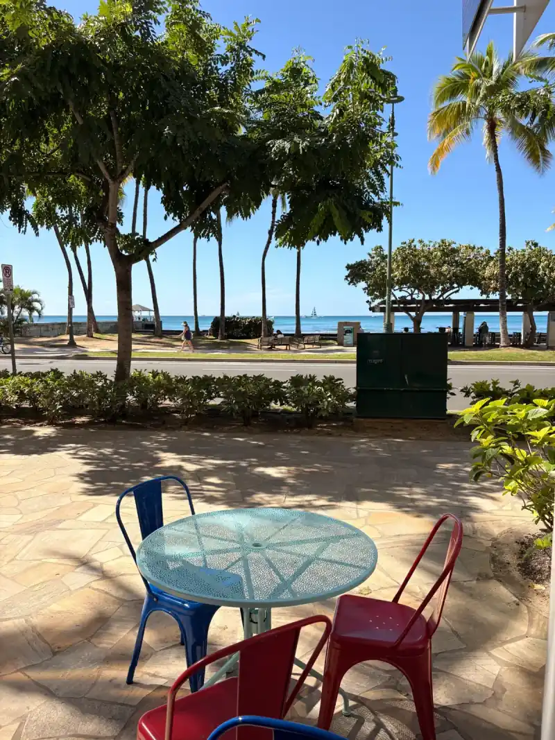 Sin Ice Stir outdoor seating area with ocean view colorful metal chairs palm trees on Kalakaua Avenue Waikiki
