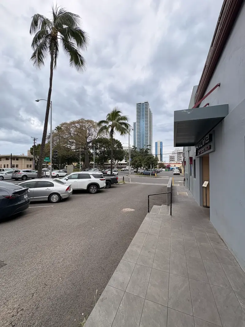 Free parking lot in front of Yakiniku Like Hawaii on Ke'eaumoku Street with palm trees and Honolulu skyline